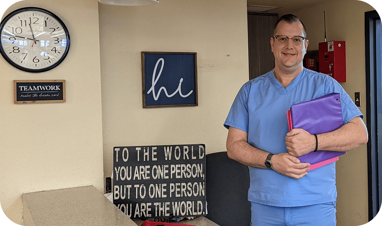 A male nurse who stands proudly at the front desk, ready to help