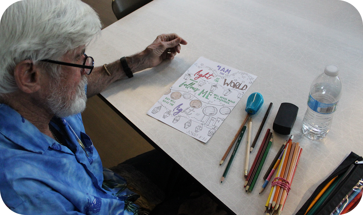 An elderly man drawing on a piece of paper