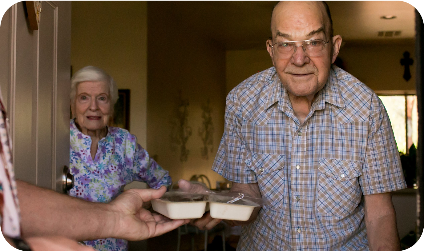 An elderly couple receiving prepackaged meals from a delivery service