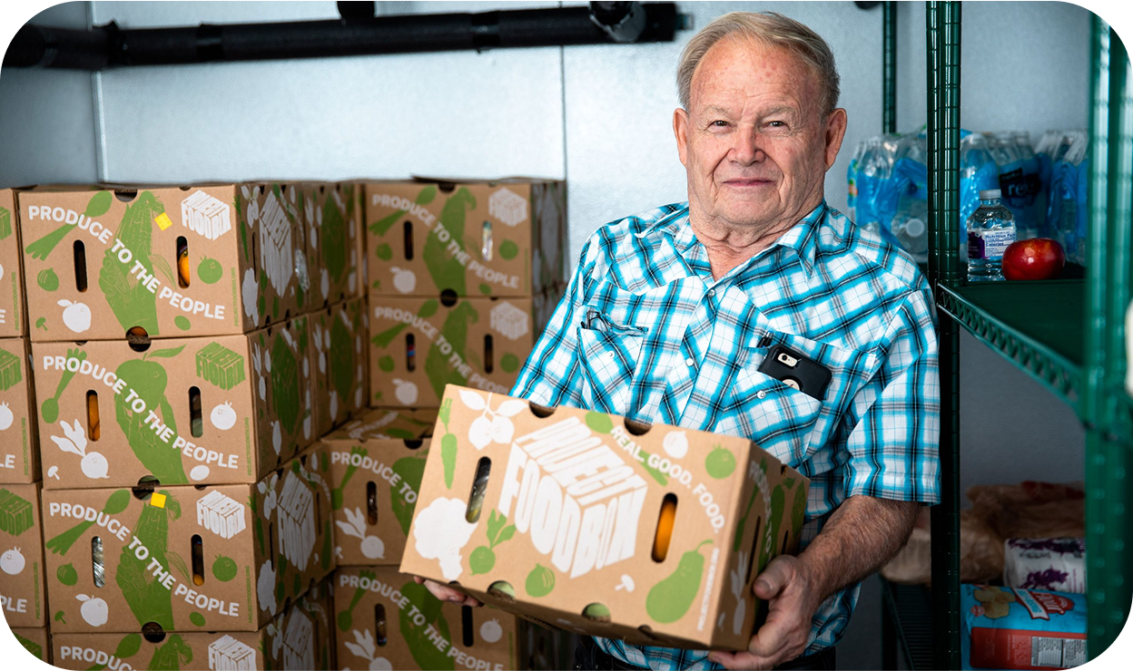 A senior man holding a box of food from a community pantry