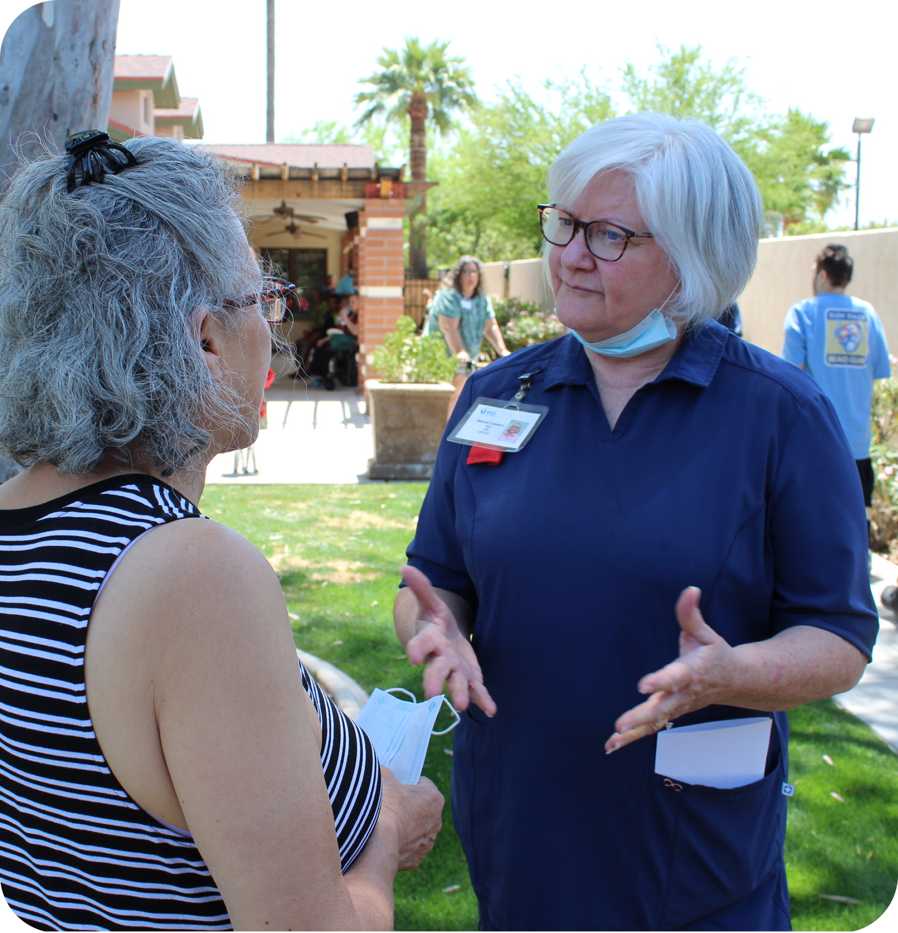An elderly woman chatting with a nurse at an event outdoors at an AllThrive 365 location