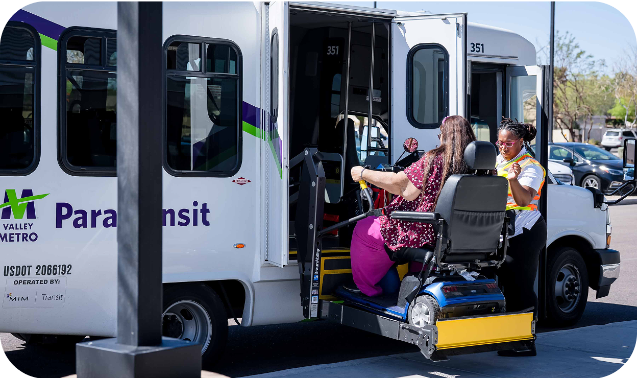 A woman who needs wheelchair access to a bus being assisted by the bus drive on a paratransit